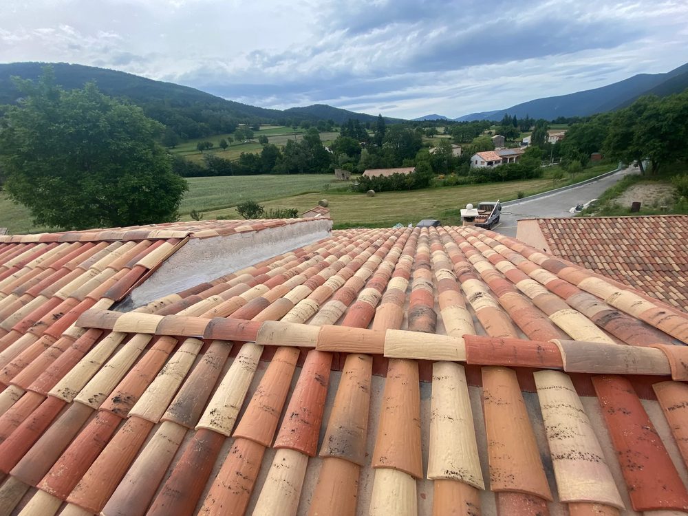 Solin et bande métallique en jonction d'une toiture en tuiles avec un mur